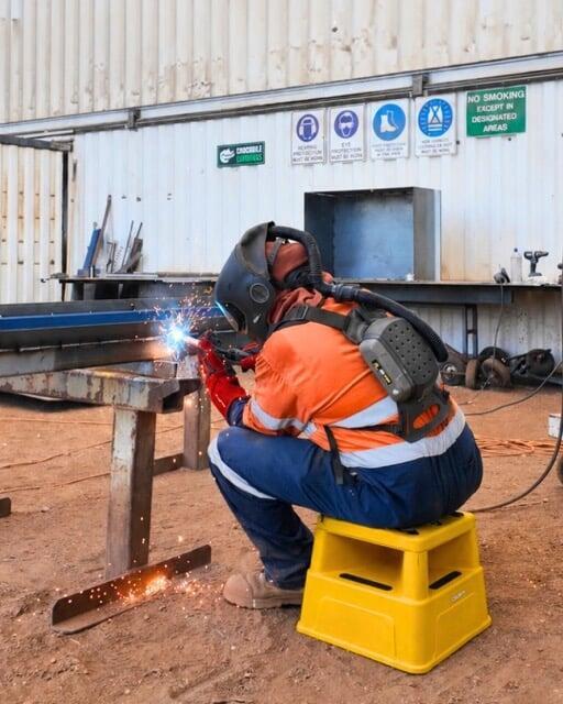 Worker fabricating steel for a custom shipping container modification
